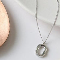 Sterling silver geometric pendant necklace with 18K gold plating, featuring modern angular design and chain detail.