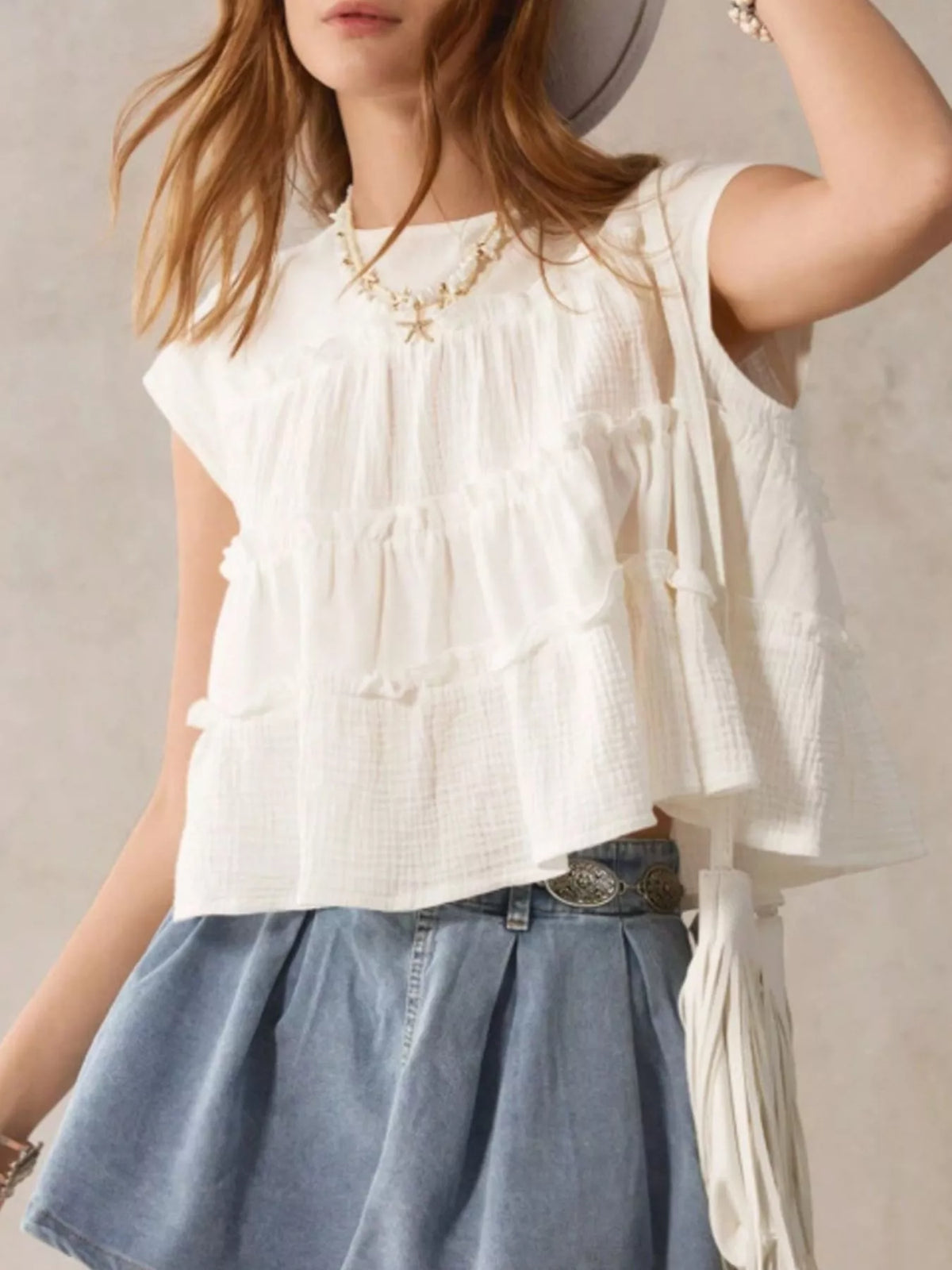 Tiered cap sleeve blouse by Trendsi, featuring layered fabric and a feminine fit, shown on a model with a soft background.