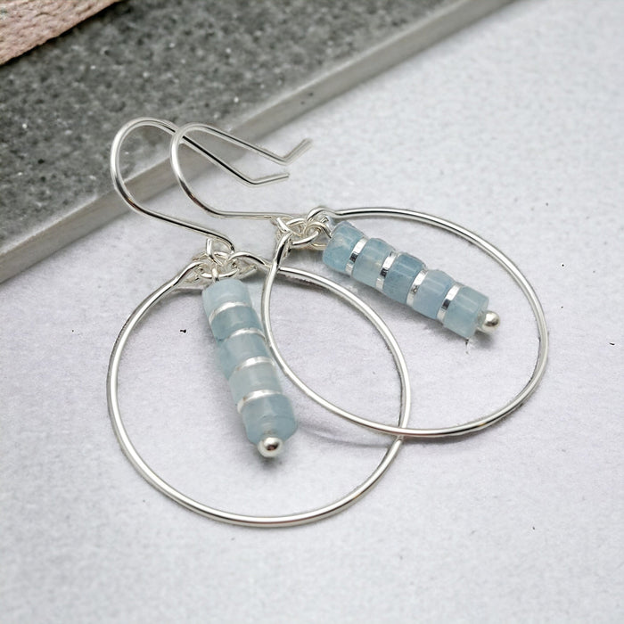 Silver boho earrings by Bijou by SAM featuring aquamarine dangle charms and intricate hoop design.