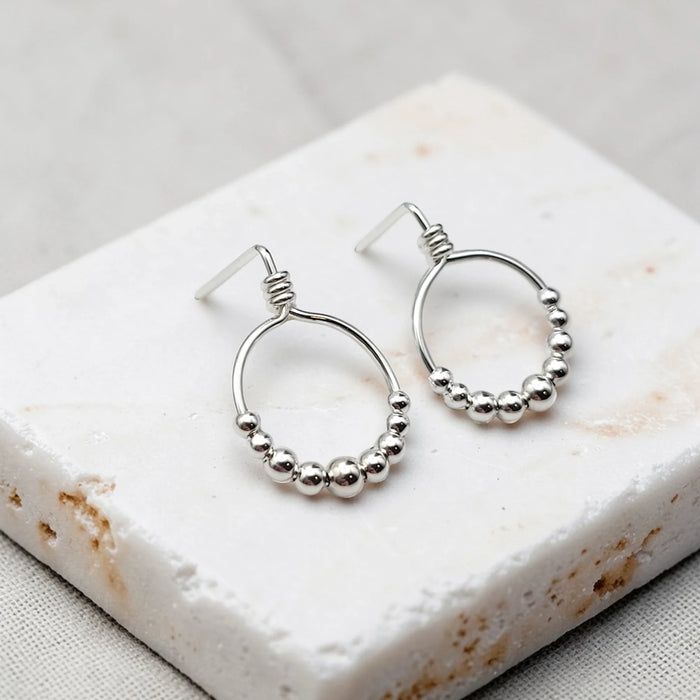 Small sterling silver hoop earrings with silver beads from Bijou by SAM, featuring a minimalist and elegant design.