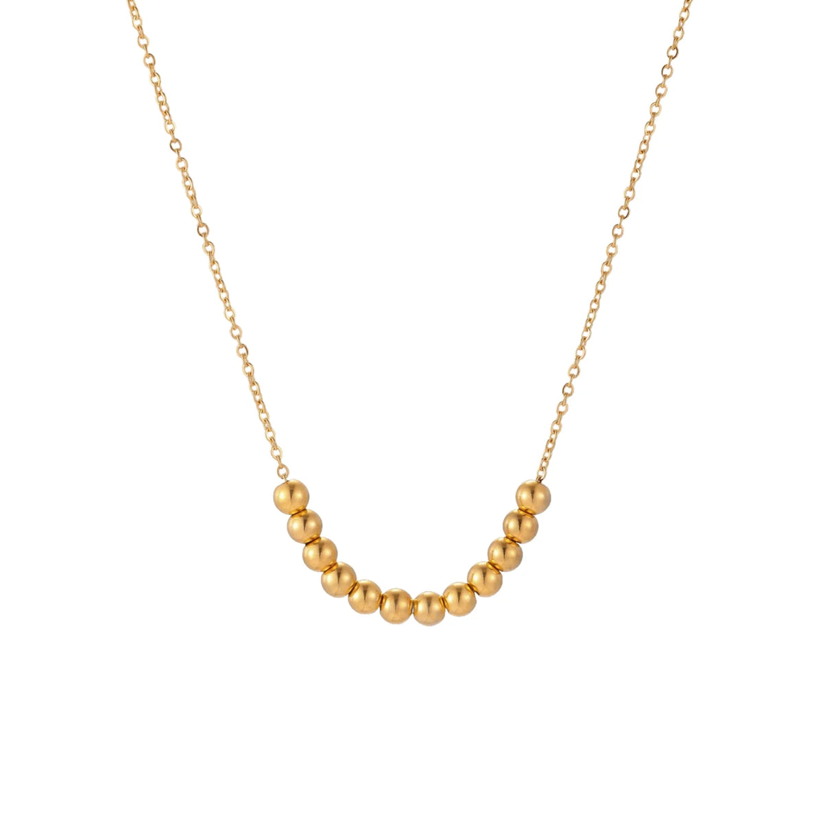 Delicate gold-plated necklace with graduated spherical beads forming gentle smile curve on beige background