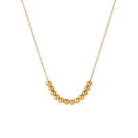 Delicate gold-plated necklace with graduated spherical beads forming gentle smile curve on beige background