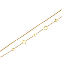Double-layer gold-plated bracelet with quatrefoil and star charms on cream background, 18K gold finish.