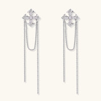White gold plated baroque cross stud earrings with long cascading zirconia chains on cream background