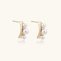 14K gold-plated curved stud earrings with three white freshwater pearls aligned vertically on cream background