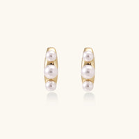 14K gold-plated curved stud earrings with three white freshwater pearls aligned vertically on cream background