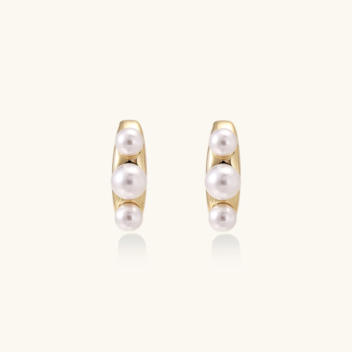 14K gold-plated curved stud earrings with three white freshwater pearls aligned vertically on cream background