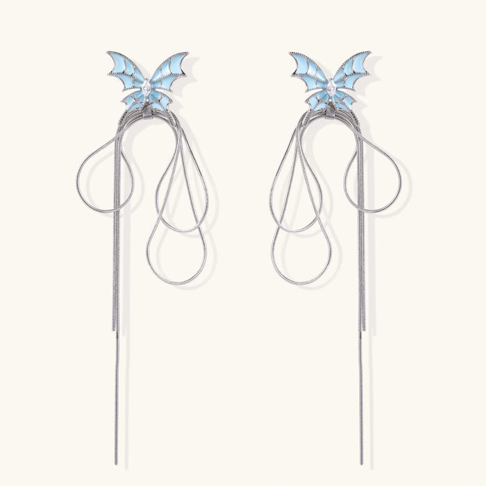 Long silver-tone earrings with powder blue enamel butterfly studs and flowing chain tassels on cream background