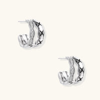 Triple-row white gold hoops with black X-pattern, twisted band, and pavé zirconia stones on white background.