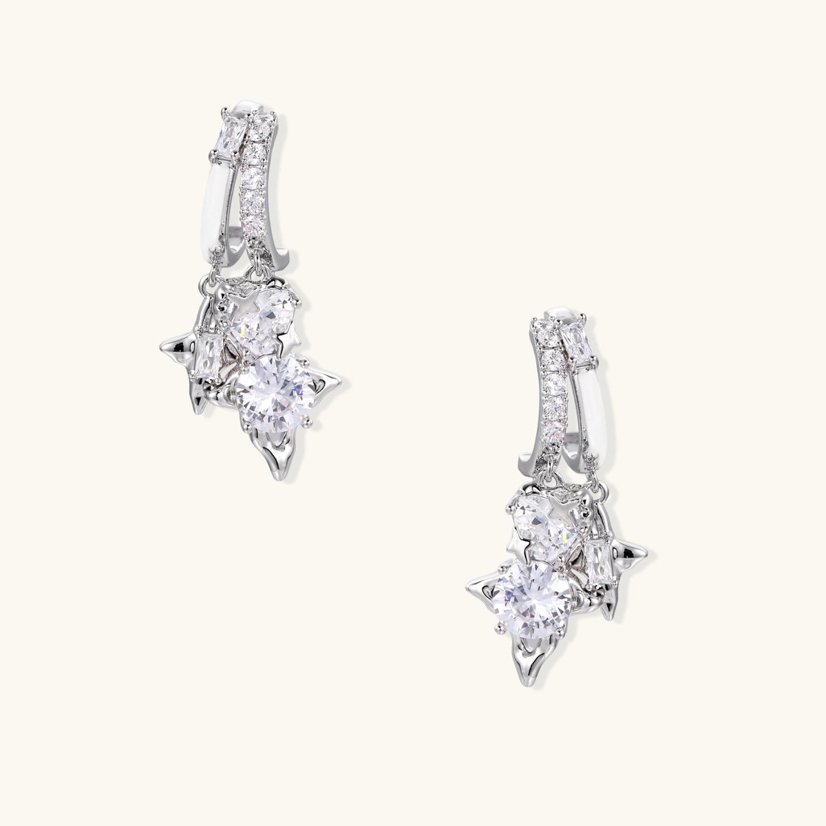 White gold-plated huggie earrings with geometric emerald-cut zirconia clusters in starburst formation on beige background