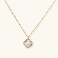 Gold quatrefoil pendant with crystal center on iridescent mother-of-pearl base, adjustable gold chain on cream background