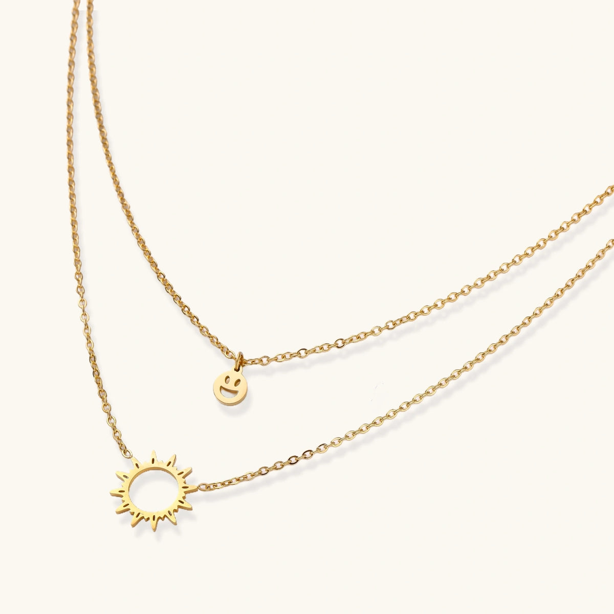 Sunshine Smiley layered necklace by The Glambox Jewels Boutique with cheerful smiley pendant and gold layered chain on a neutral background