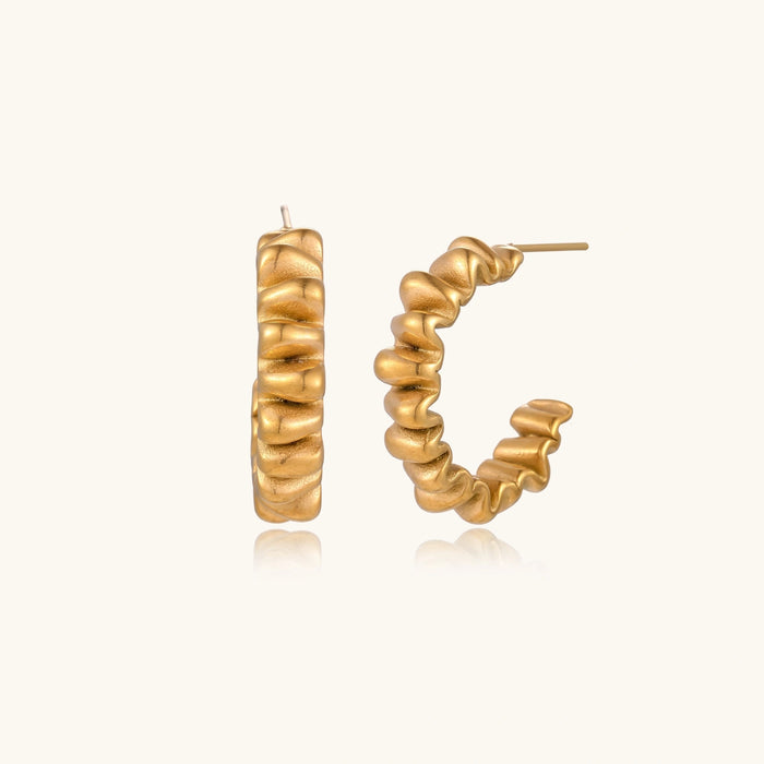 Twisted gold hoop earrings from The Glambox Jewels Boutique, showcasing shiny gold hoops with a twisted design.