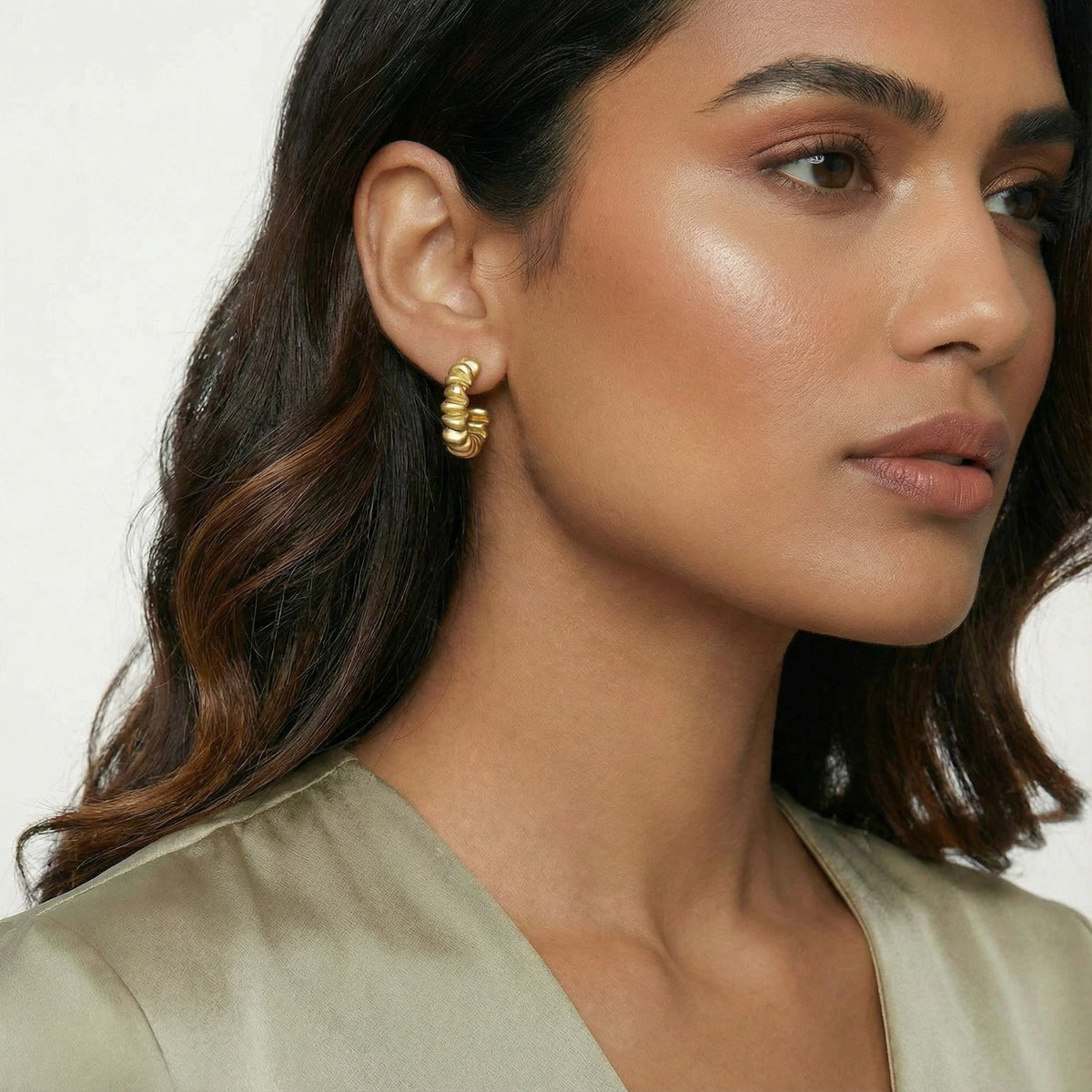 Twisted gold hoop earrings from The Glambox Jewels Boutique, featuring bold, intertwined design for a stylish look.