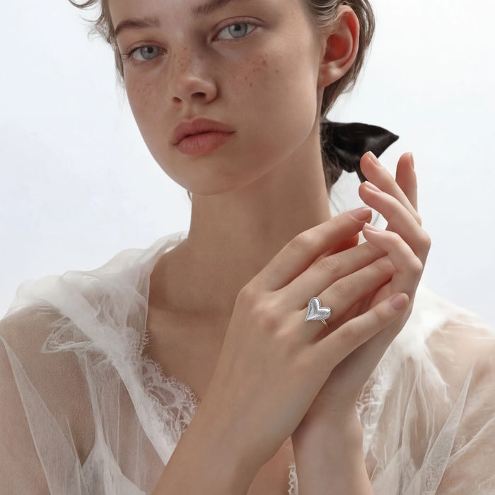 Feathered Heart Ring from The Glambox Jewels Boutique, silver-toned ring with detailed feather and heart design, on a white background.