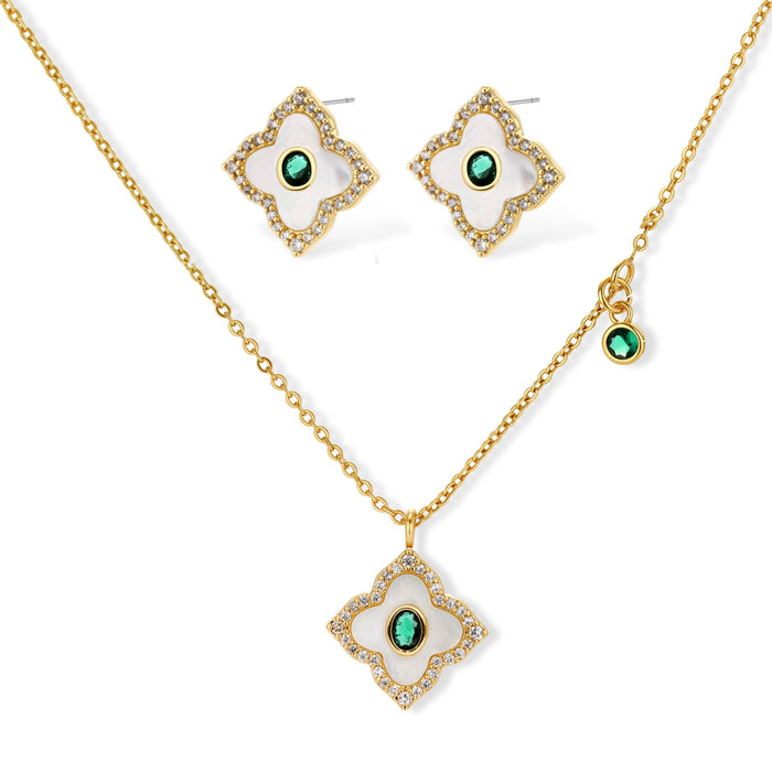Gold-plated quatrefoil pendant and earrings with white enamel, emerald CZ center stones, and crystal borders on white background.
