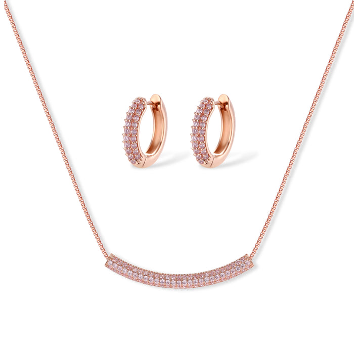 Rose gold jewelry set with pavé cubic zirconia stones including curved necklace, hoop earrings, and adjustable ring on cream background.
