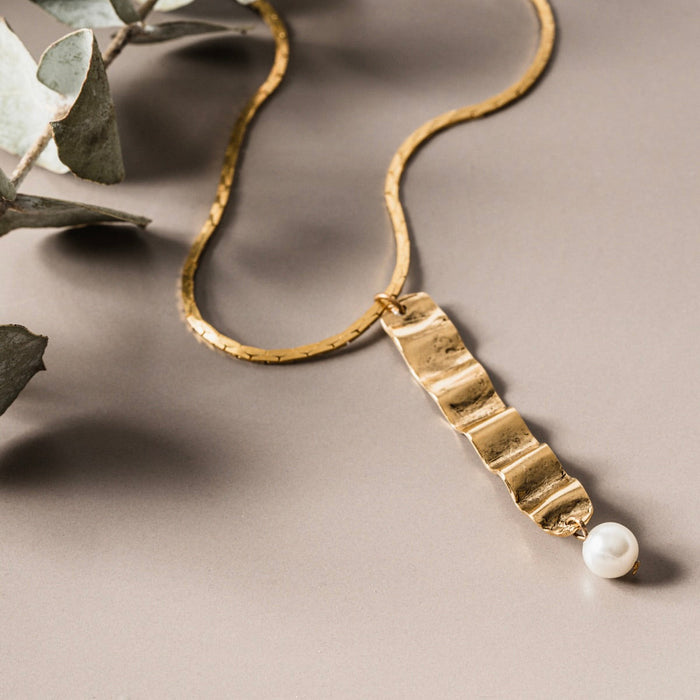 Tillydoro wave and pearl necklace featuring a delicate chain with wave-shaped design and lustrous pearls on a white background.