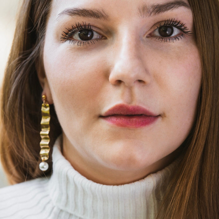 Tillydoro wave and pearl earrings featuring elegant silver waves with dangling white pearls on a white background.