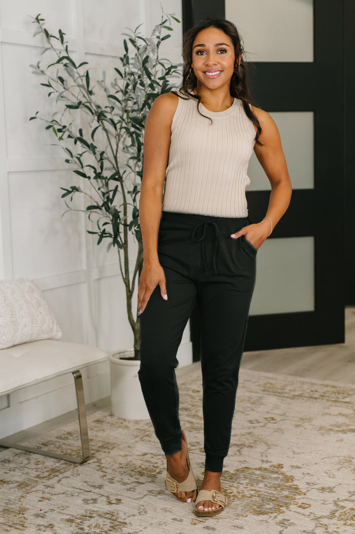 Black Sweat It high-waisted joggers from Ave Shops, showing the relaxed fit and elastic waistband on a model.