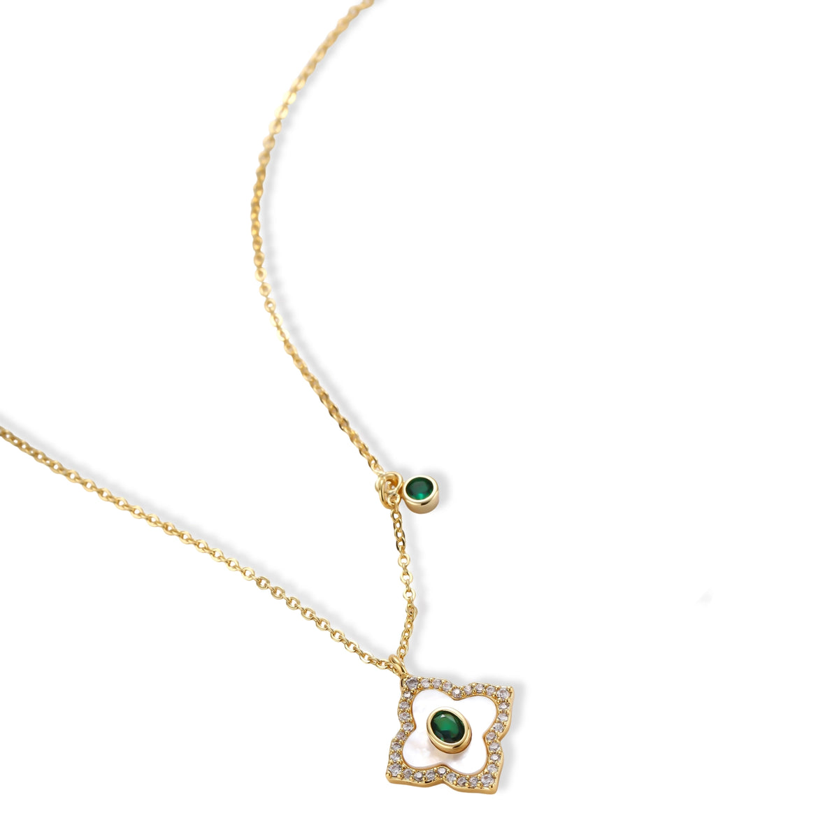 Gold-plated quatrefoil pendant and earrings with white enamel, emerald CZ center stones, and crystal borders on white background.