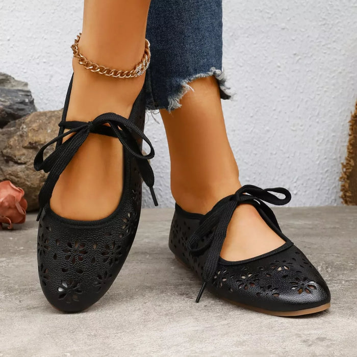Floral cutout tied slip-on shoes by Trendsi featuring a stylish design with floral cutouts and tied front details.