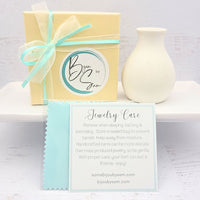 Small gold circle earrings from Bijou by SAM's Aiden collection displayed in packaging.